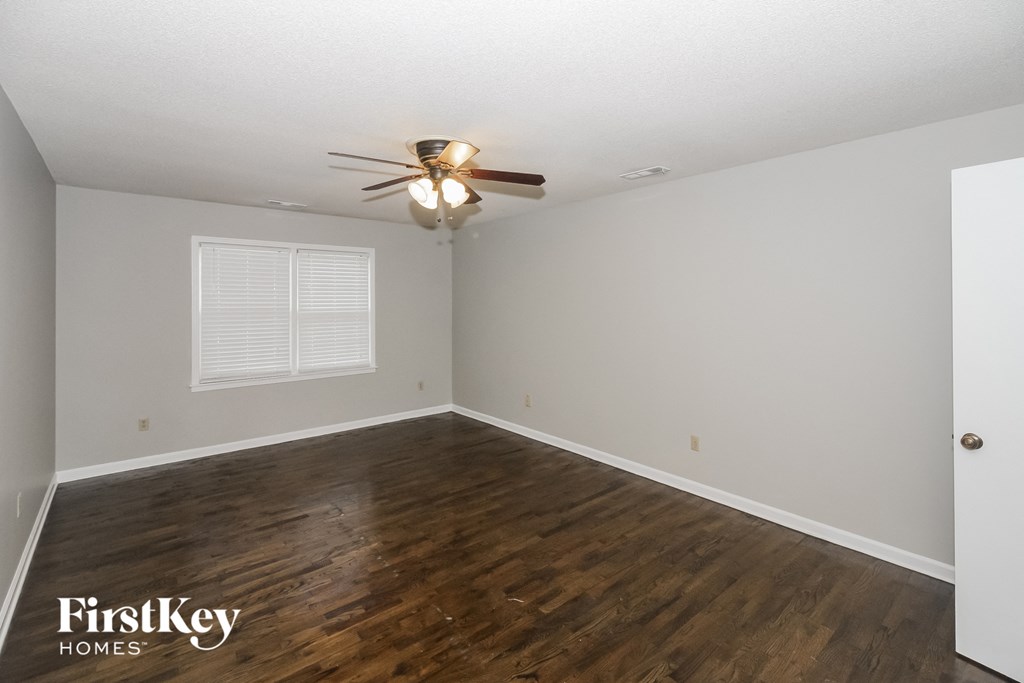 the living room of an empty house with wood flooring and a ceiling fan