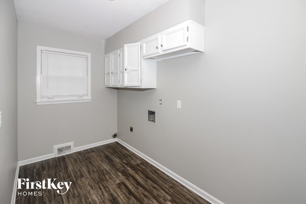 a room with white cabinets and a window and wood floors