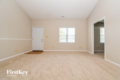 a spacious living room with white carpet and a white door