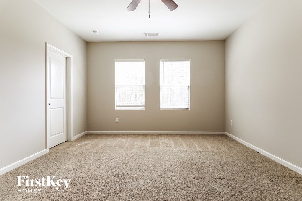 a empty room with two windows and a ceiling fan
