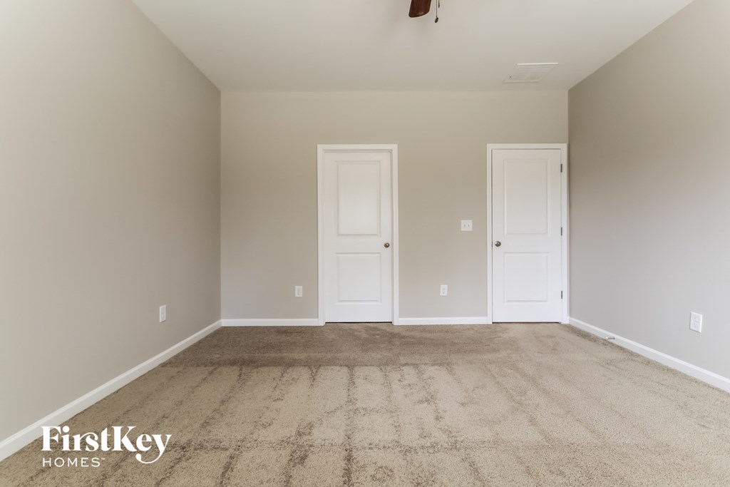 a empty living room with carpet and two doors