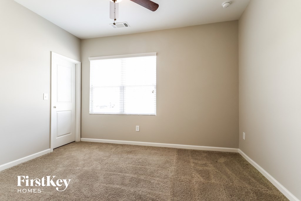 a carpeted room with a window and a ceiling fan