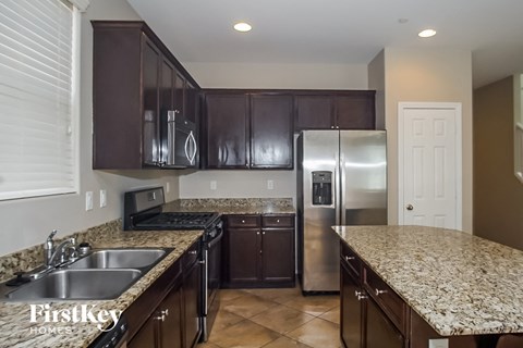 A kitchen with brown cabinets and granite countertops.