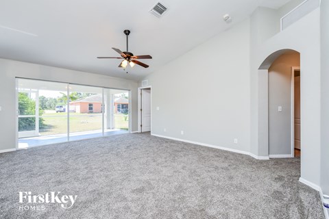 A spacious room with a ceiling fan and carpeted floor.