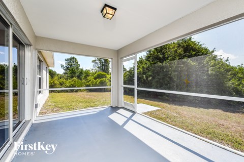 A sunny balcony with a view of trees and grass.