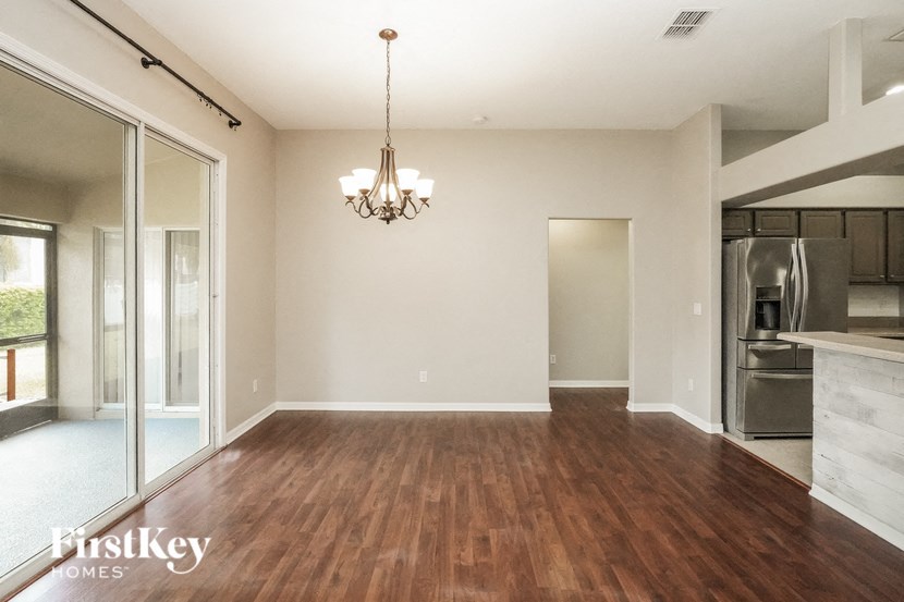 A large empty room with wooden floors and a chandelier hanging from the ceiling.