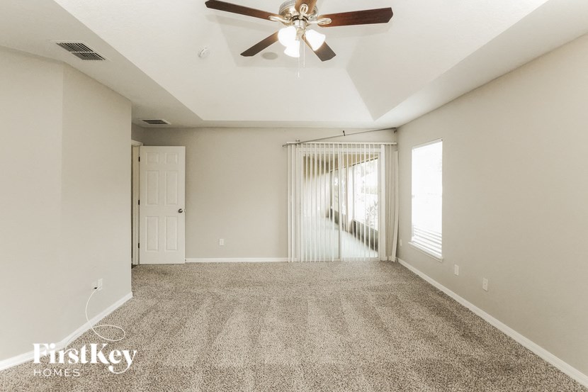 A spacious room with a ceiling fan and carpeted floor.