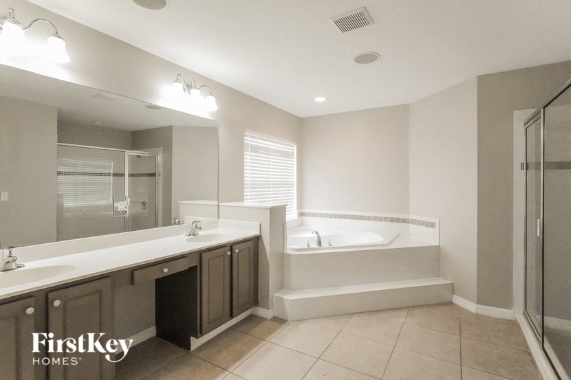 A bathroom with a tub, sink, and mirror.