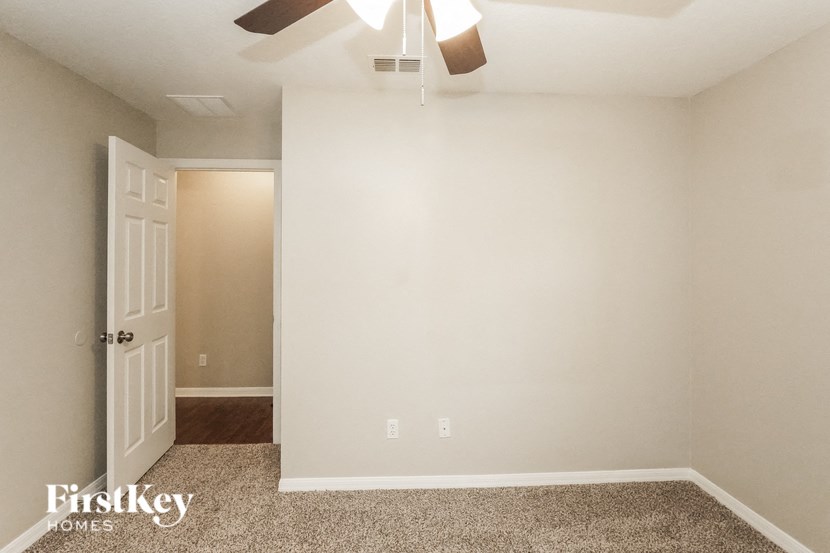 A room with a ceiling fan and a door.
