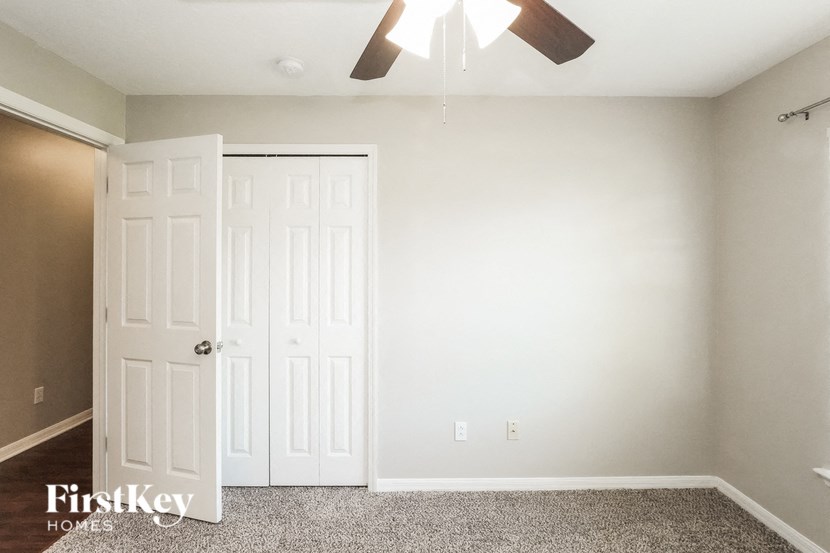 A room with a carpeted floor and a ceiling fan.