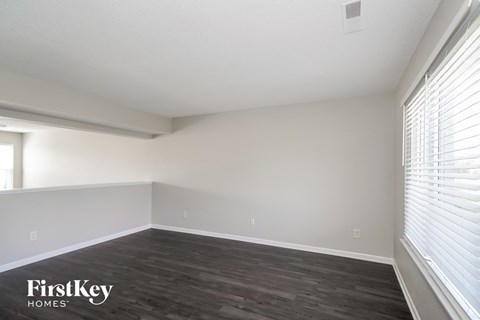 the spacious living room with wood flooring and white walls