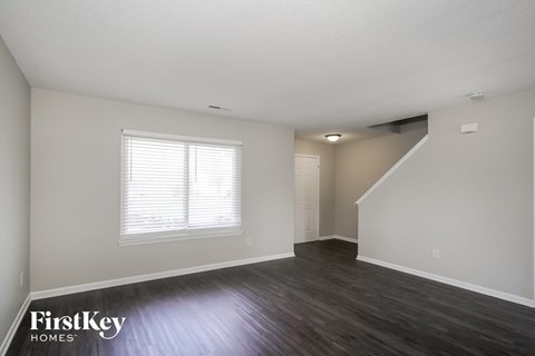 the living room of an apartment with wood flooring and a window