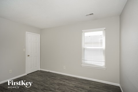 a bedroom with a white door and a window and a wood floor