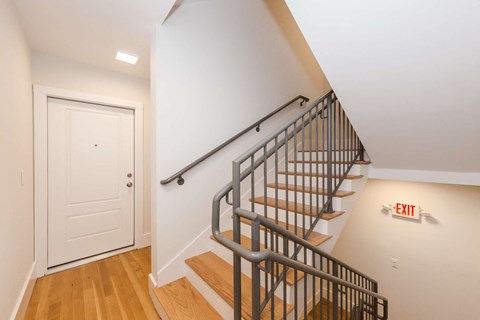 a staircase in a home with a white door and wood floors