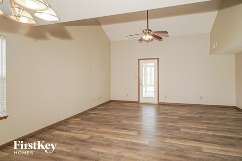 the spacious living room with wood floors and a ceiling fan