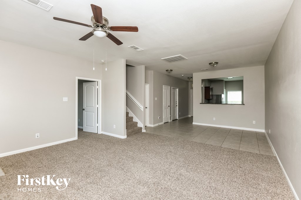 a spacious living room with carpet and a ceiling fan