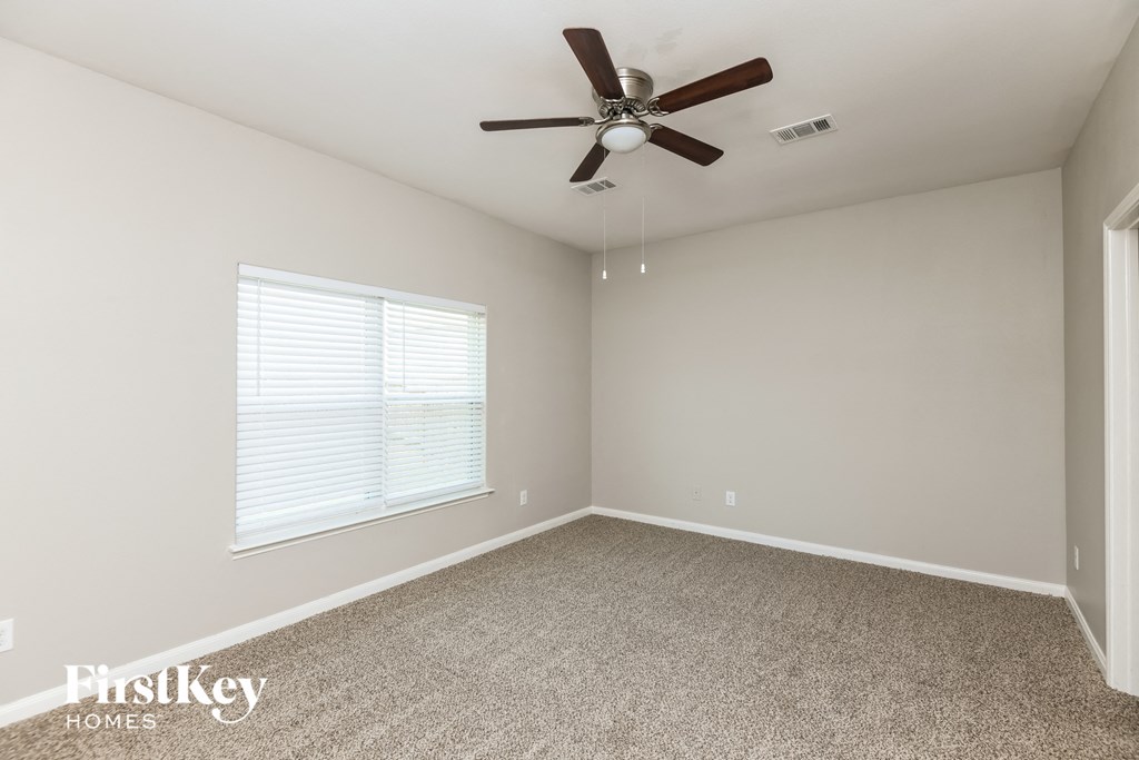 an empty room with a ceiling fan and a window