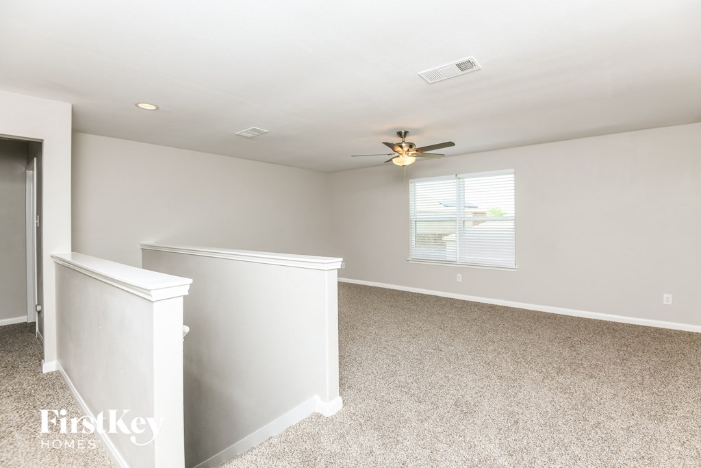a bonus room with white walls and a ceiling fan
