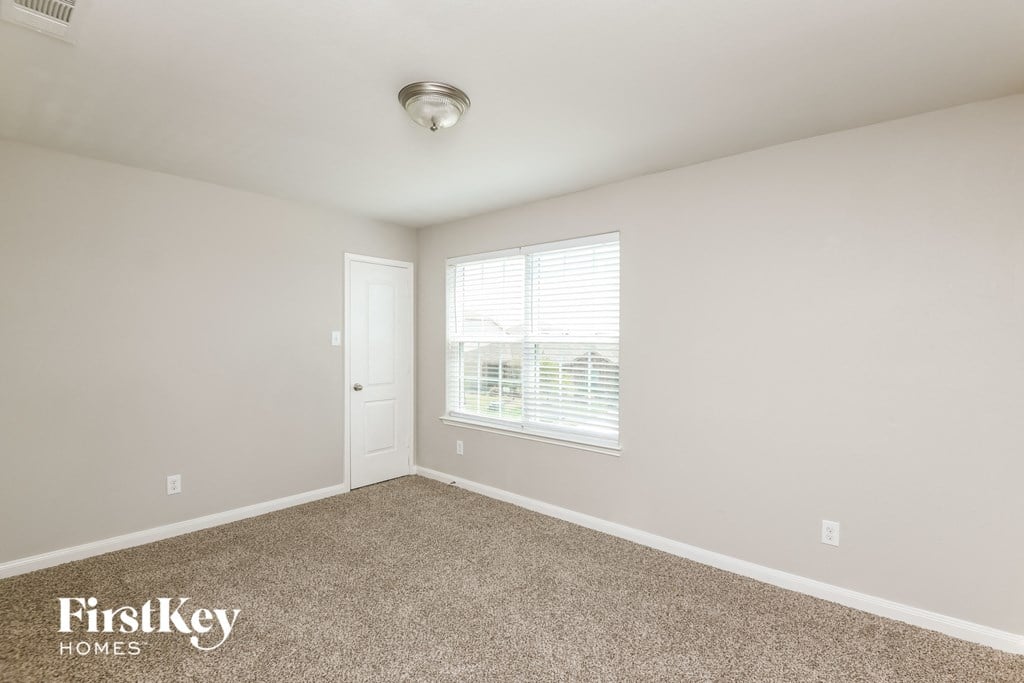 a bedroom with carpet and a window and a door