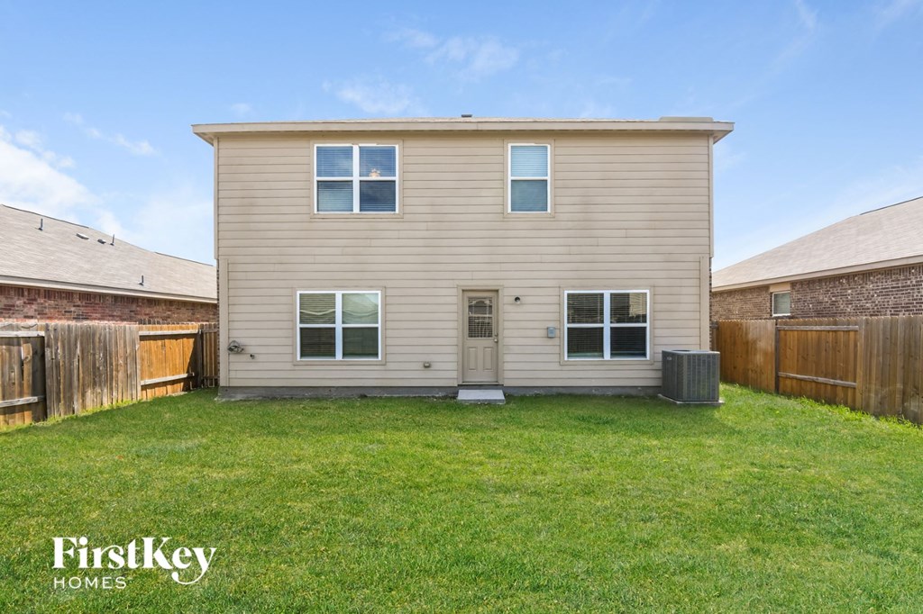 a tan house with a yard and a wooden fence
