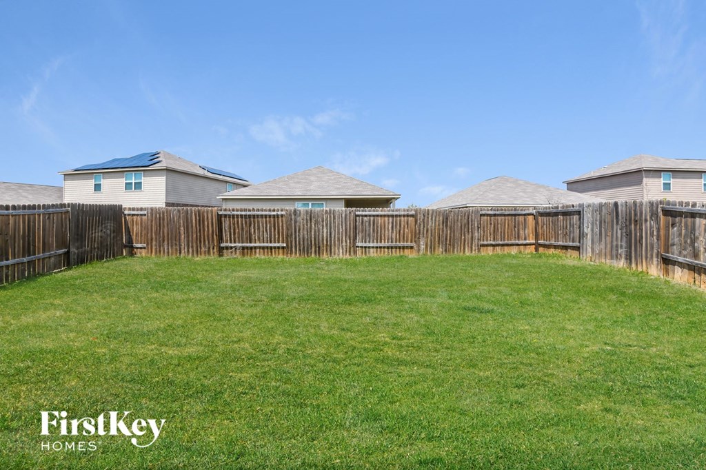 a backyard with a fence and houses in the background