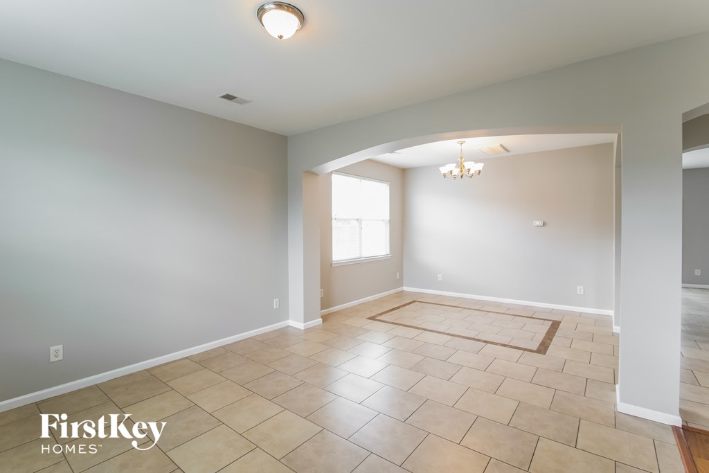 A spacious room with a tiled floor and a chandelier hanging from the ceiling.
