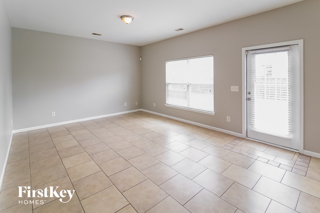 A spacious room with tile flooring and a sliding glass door.