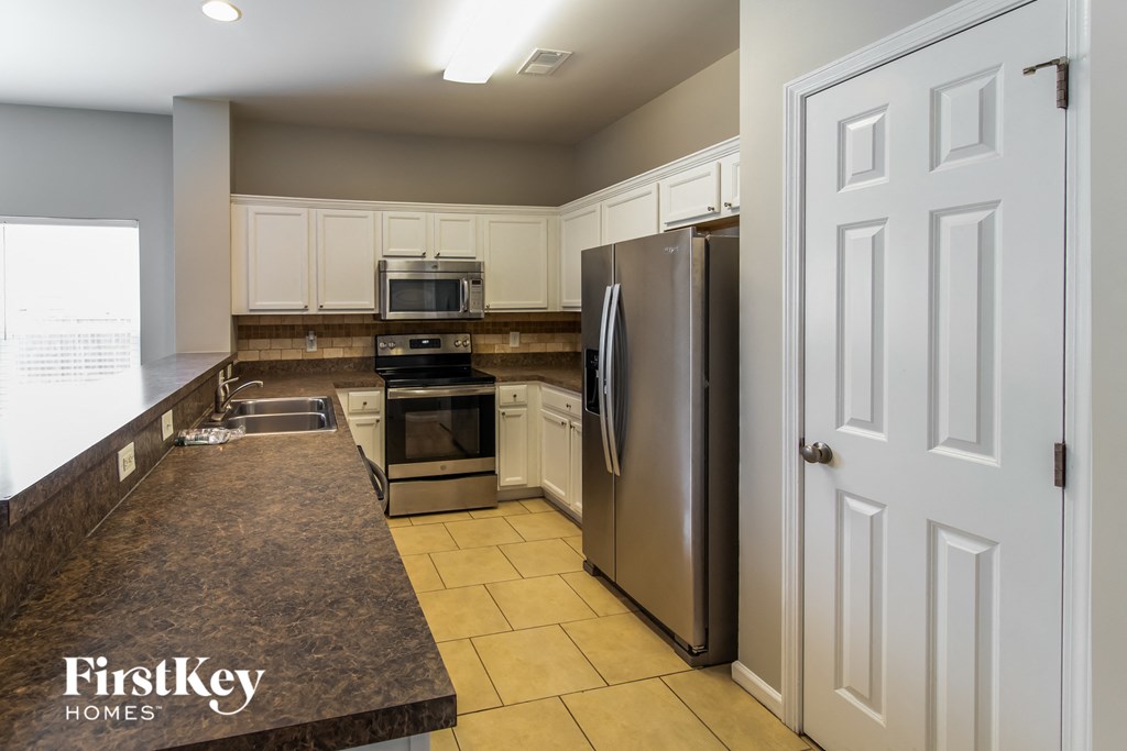 A kitchen with a refrigerator, oven, and microwave.