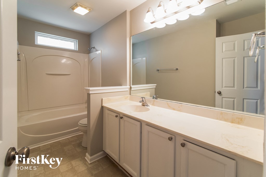 A bathroom with a tub, sink, and mirror.