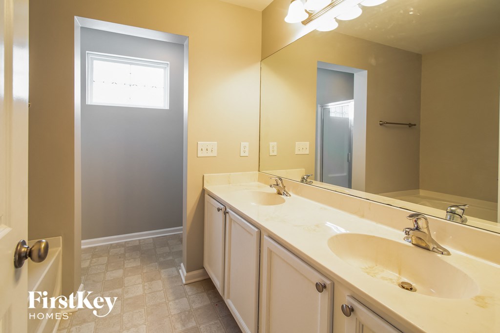 A bathroom with a sink, mirror, and light switches.