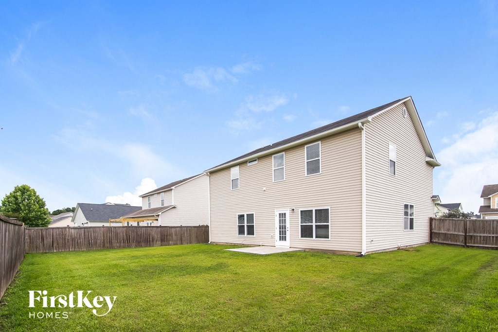 A house with a fence and a blue sky in the background.