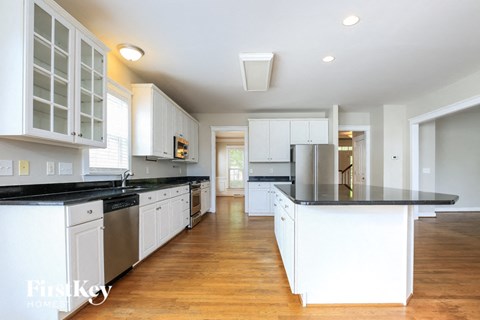 A kitchen with white cabinets and black countertops.