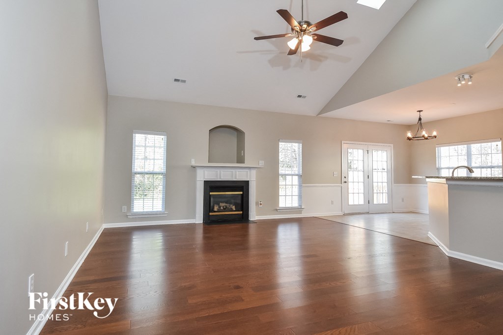 an empty living room with a fireplace and a ceiling fan