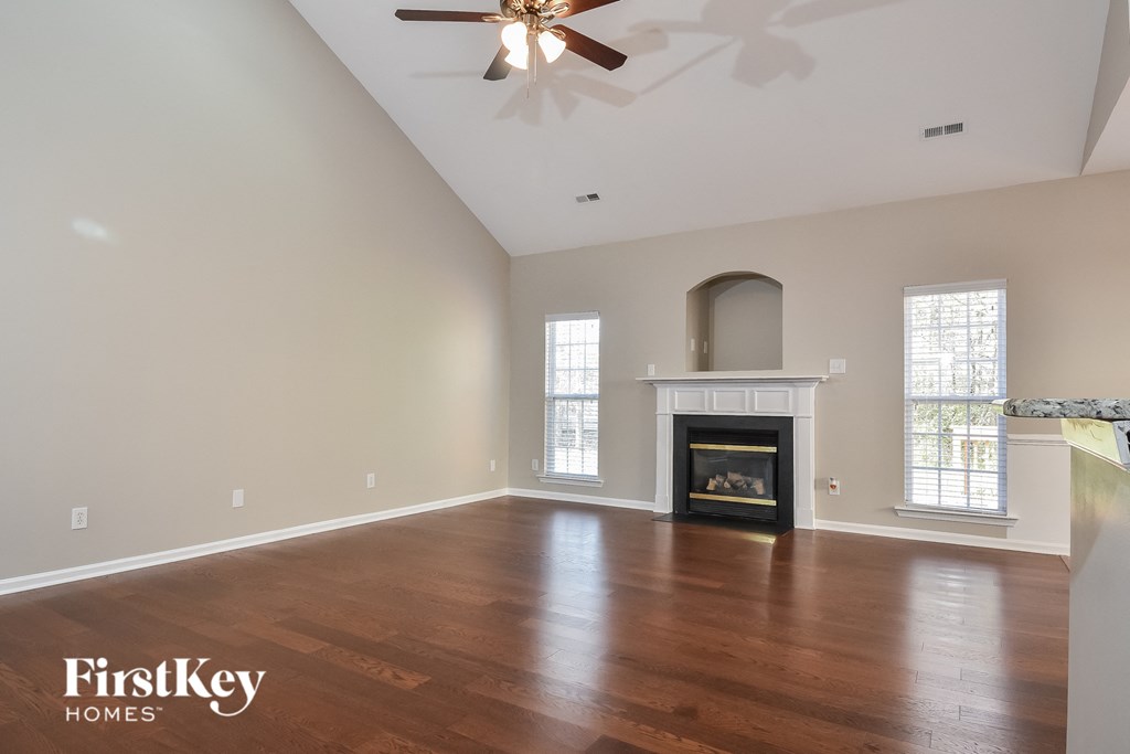 an empty living room with a fireplace and a ceiling fan