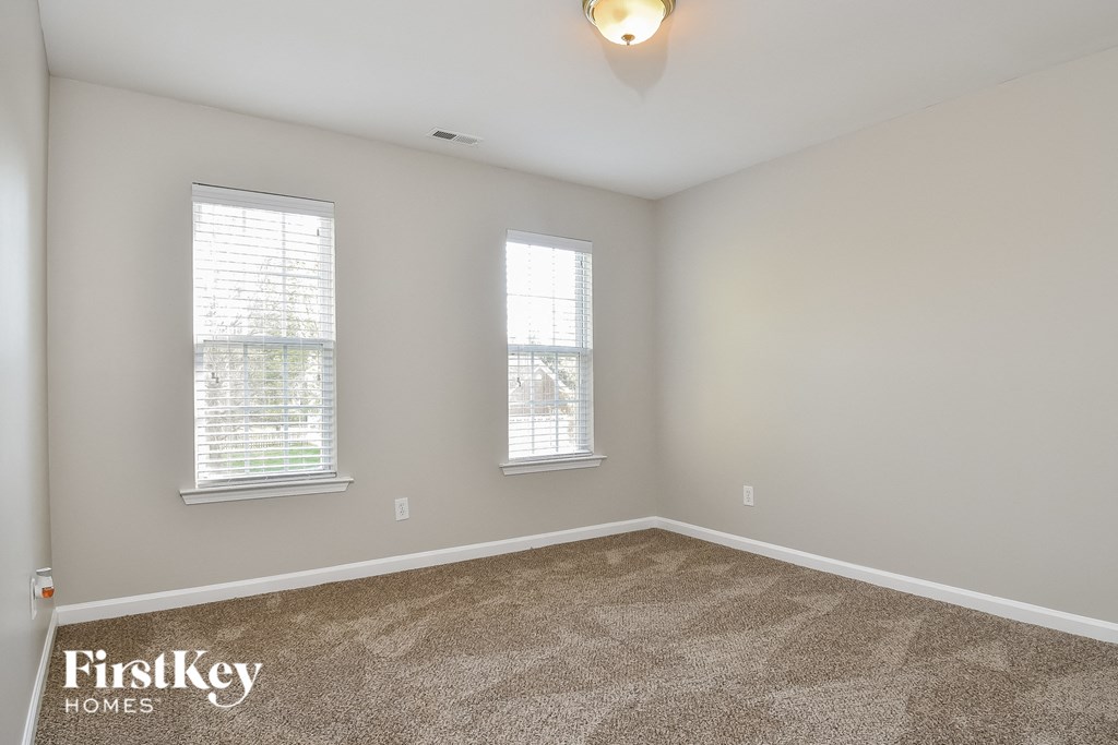 a bedroom with carpet and two windows