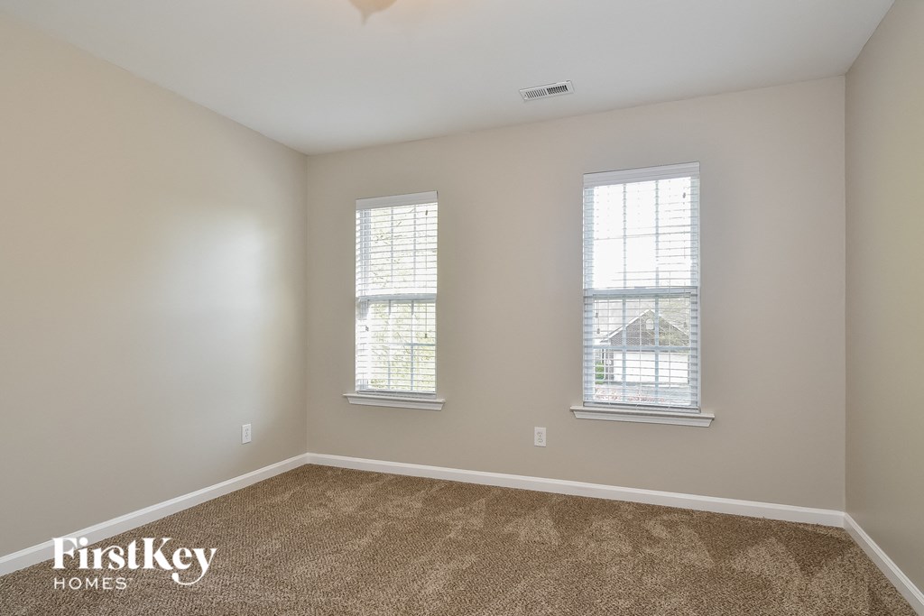 a bedroom with two windows and a carpeted floor