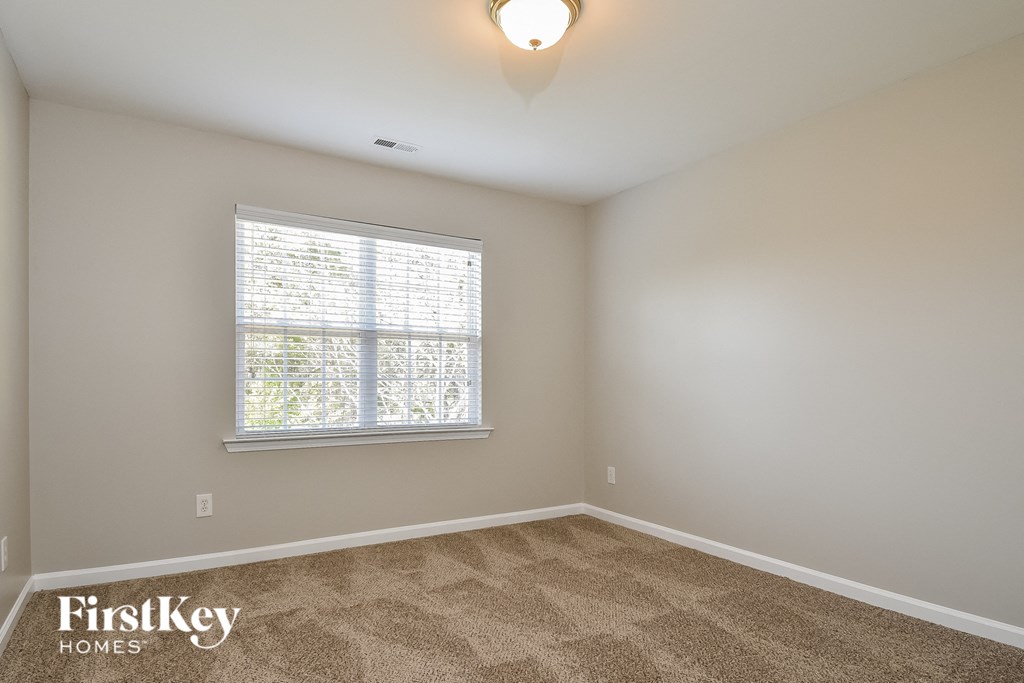 the second bedroom is spacious and has carpeted floors and a large window