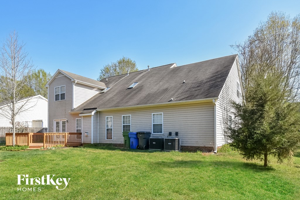 the front of a white house with a yard and a deck