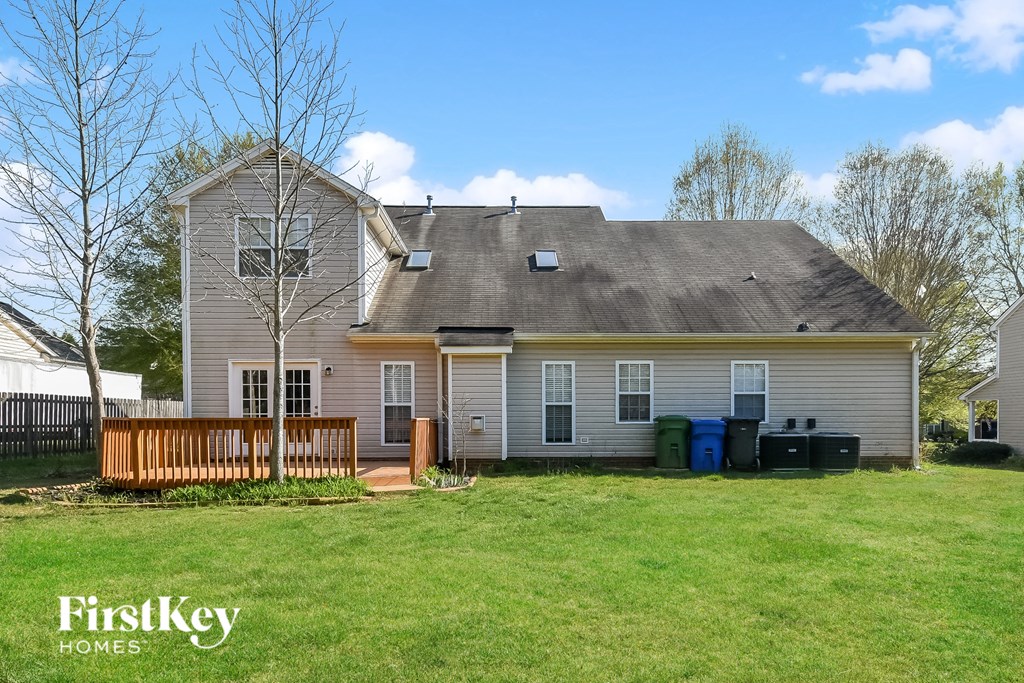 the front of a white house with a yard and a deck