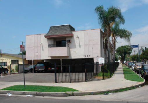 an old white building with a palm tree in front of it