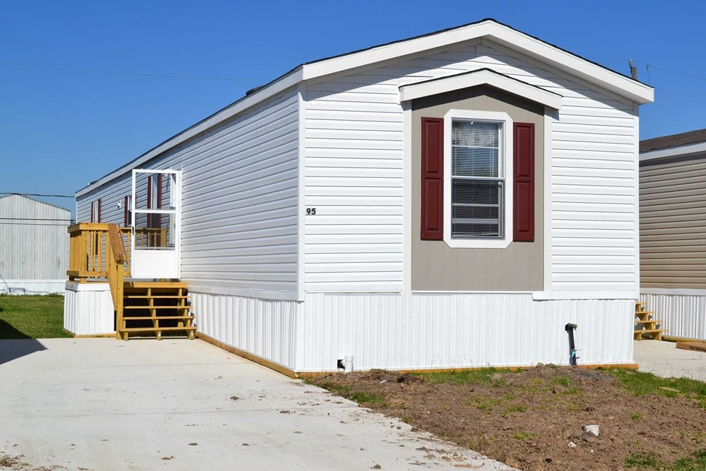a small white house with a sidewalk in front of it