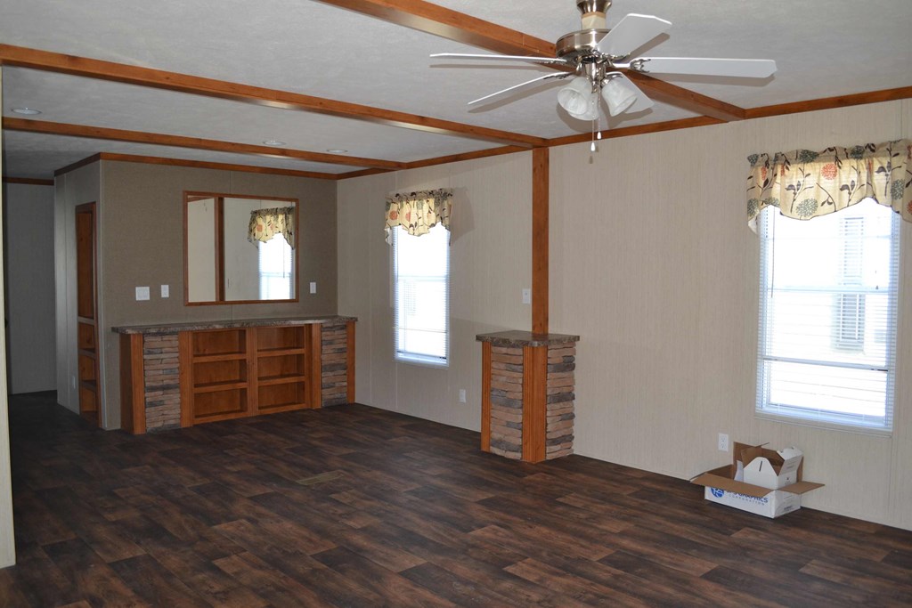 an empty living room with wood floors and a ceiling fan