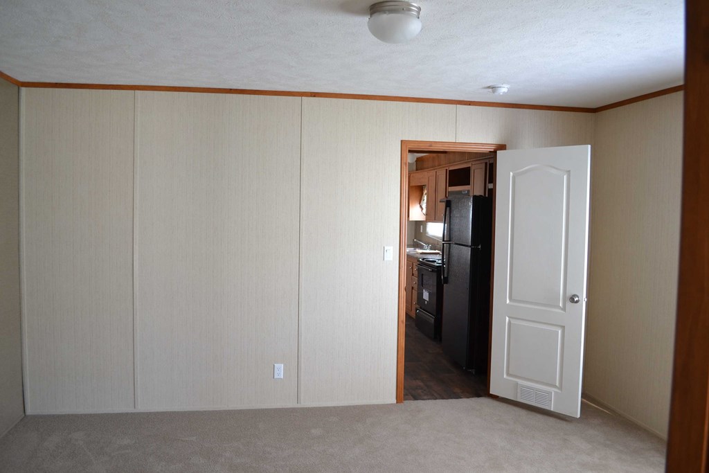 an empty living room with a door to a kitchen
