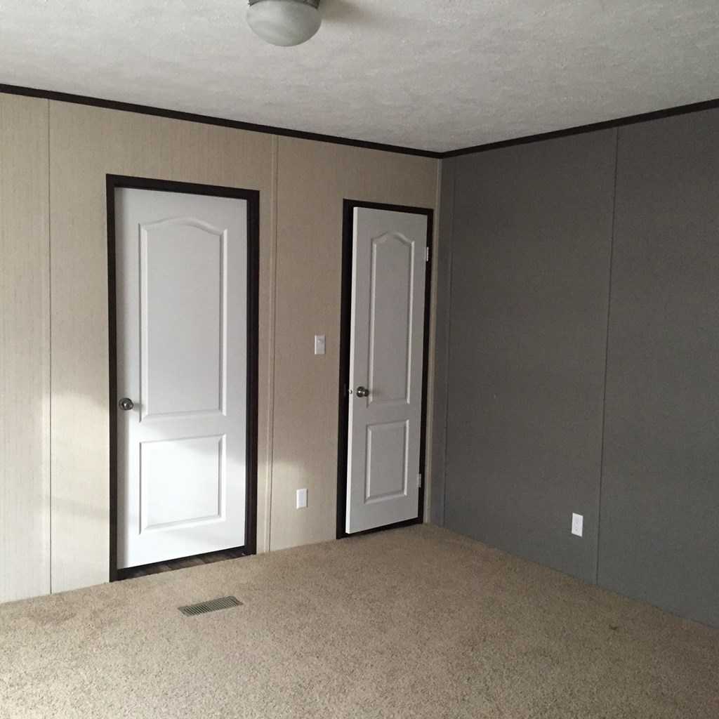an empty living room with a white door and a closet