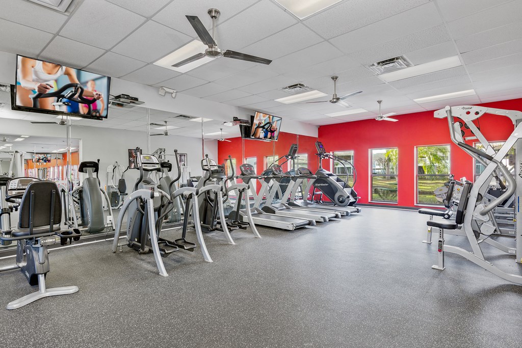 a gym with various cardio machines and flat screen tv