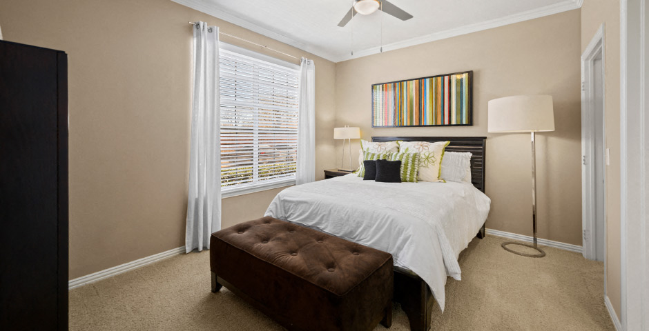 Spacious master bedroom with attached master bathroom and walk-in closet, ceiling fan and 9-foot ceilings at The Lanesborough Apartments in Houston.