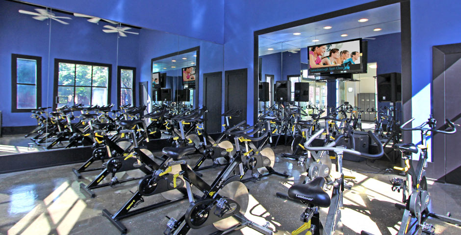 Luxury apartments with huge fitness center with multiple varieties of workout equipment, free weights, yoga and spin rooms at The Lanesborough Apartments in Houston