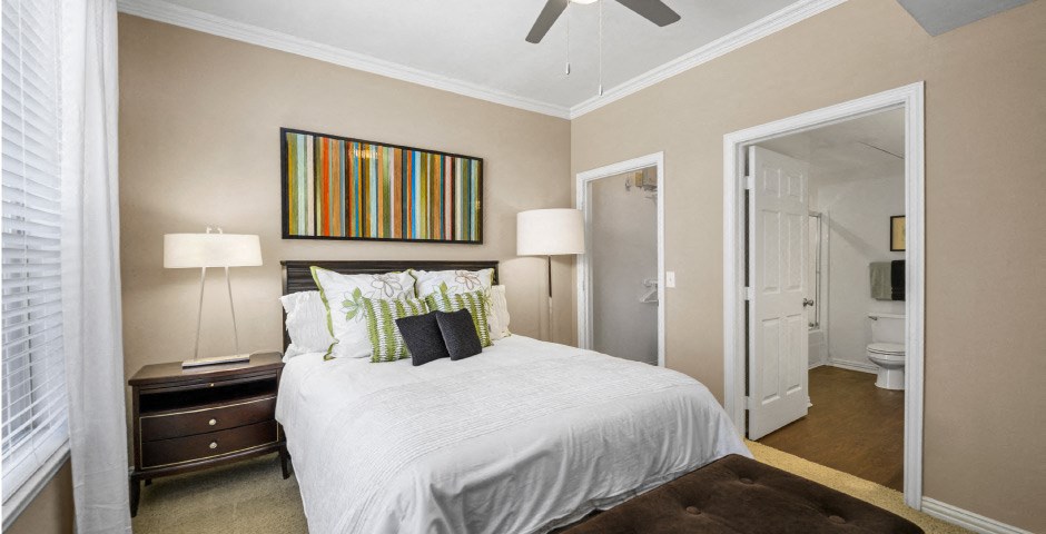 Spacious master bedroom with attached master bathroom and walk-in closet, ceiling fan and 9-foot ceilings at The Lanesborough Apartments in Houston.