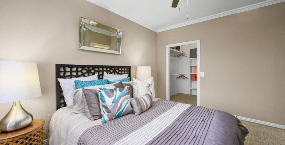 Spacious bedroom with walk-in closet and ceiling fan at The Lanesborough Apartments in Houston.