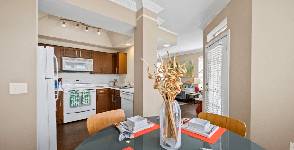 Spacious dining room with wood grain plank flooring, oversized windows, spacious kitchen with white appliances and side by-by-side refrigerators The Lanesborough Apartments in Houston.